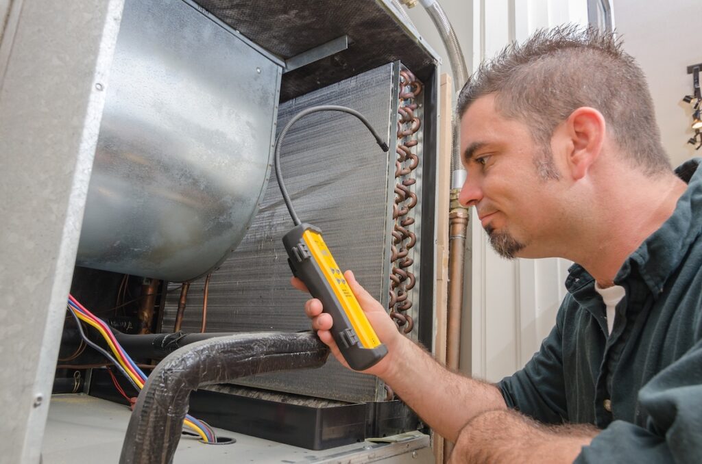 emergency hvac An Hvac technician searching for a refrigerant leak on an evaporator coil.