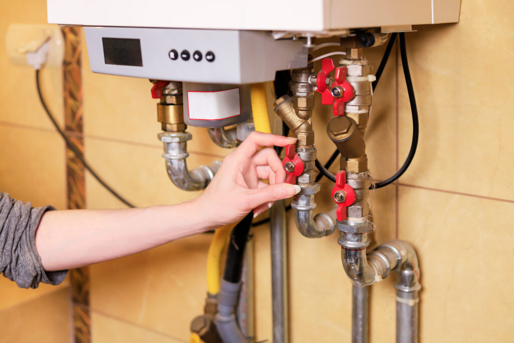 boiler A woman checks if everything is OK with the gas furnace heating water in the house. Housework