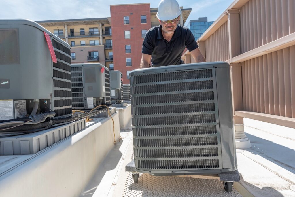 how much to replace a heating and air conditioning system Hvac technician rolling a new air conditioner for an install