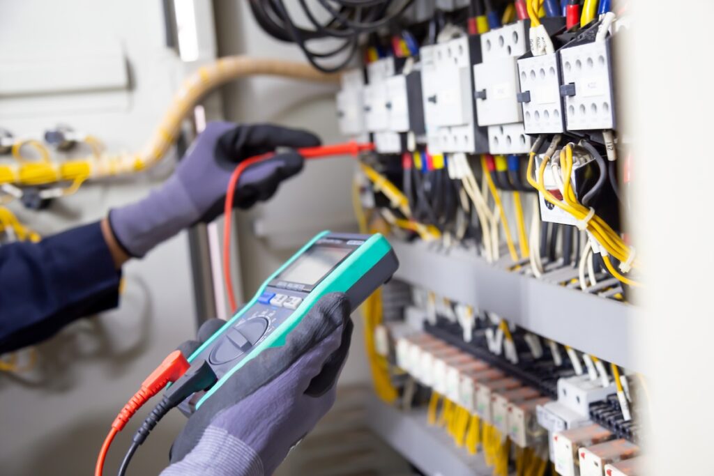 Electrician engineer tests electrical installations and wires on relay protection system. Adjustment of scheme of automation and control of electrical equipment.