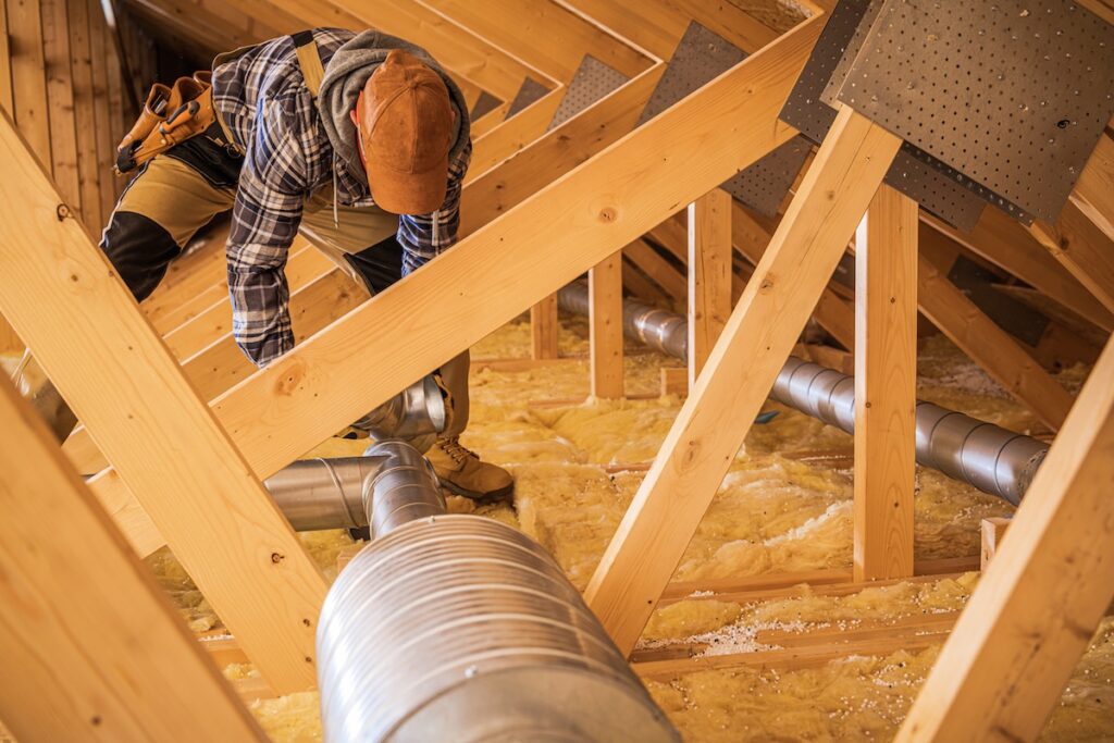 how to clean air ducts Professional HVAC Technician Installing Air Ducts in the Wooden Roof Section of the Building. Ventilation Systems Theme.