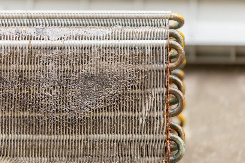 A close-up of a heavily soiled and dusty evaporator coil before a professional treatment with an AC Coil Cleaner to restore airflow and cooling efficiency.