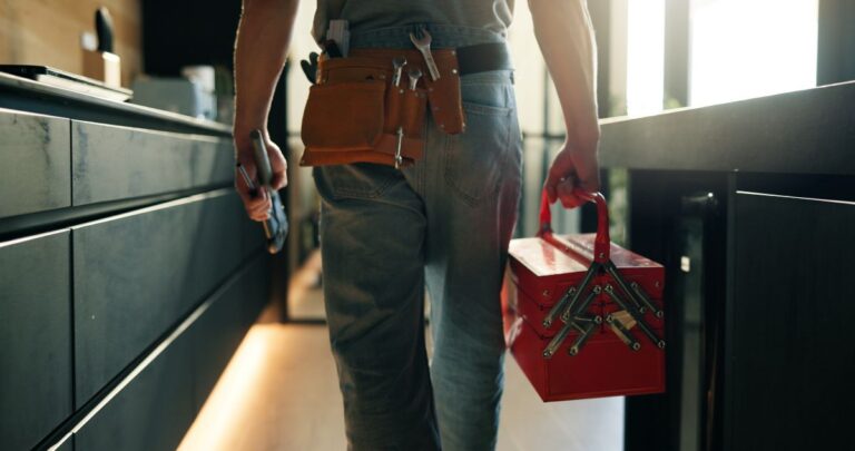 plumbing davison worker carrying toolbox inside kitchen