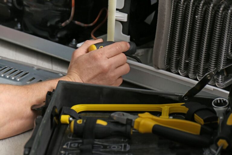 refrigeration clarkston hand using screwdriver to repair fridge