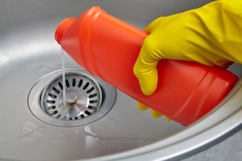 clogged drain deep in pipe yellow glove holding cleaning product