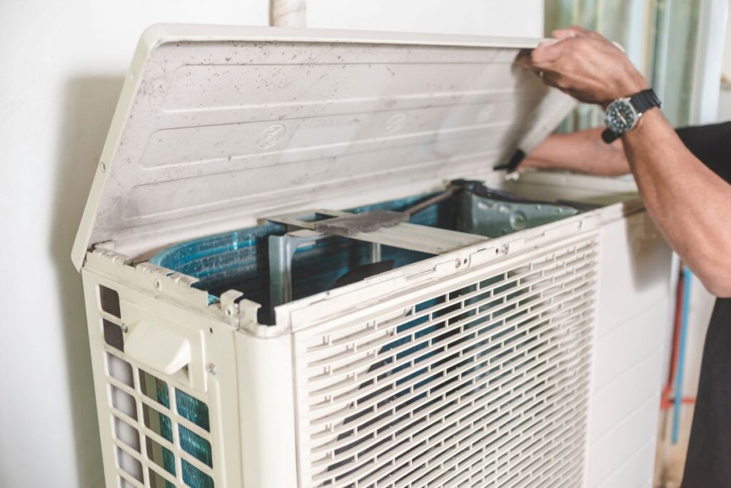 ac maintenance hands opening old white unit 