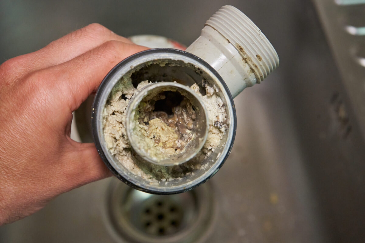 sewer drain cleaning in the hands of a clogged dirty sewer pipe from leftover food