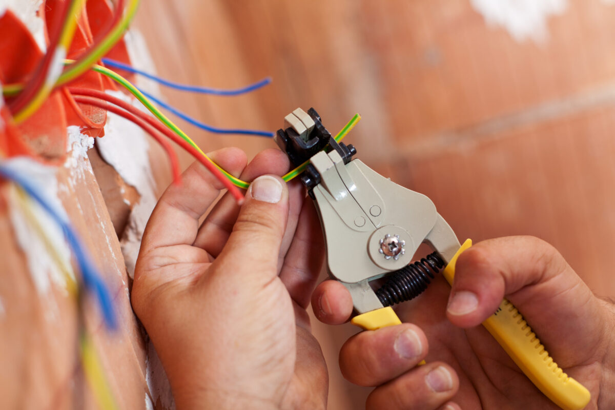 electrician swartz creek Electrician peeling off insulation from wires - closeup on hands and pliers