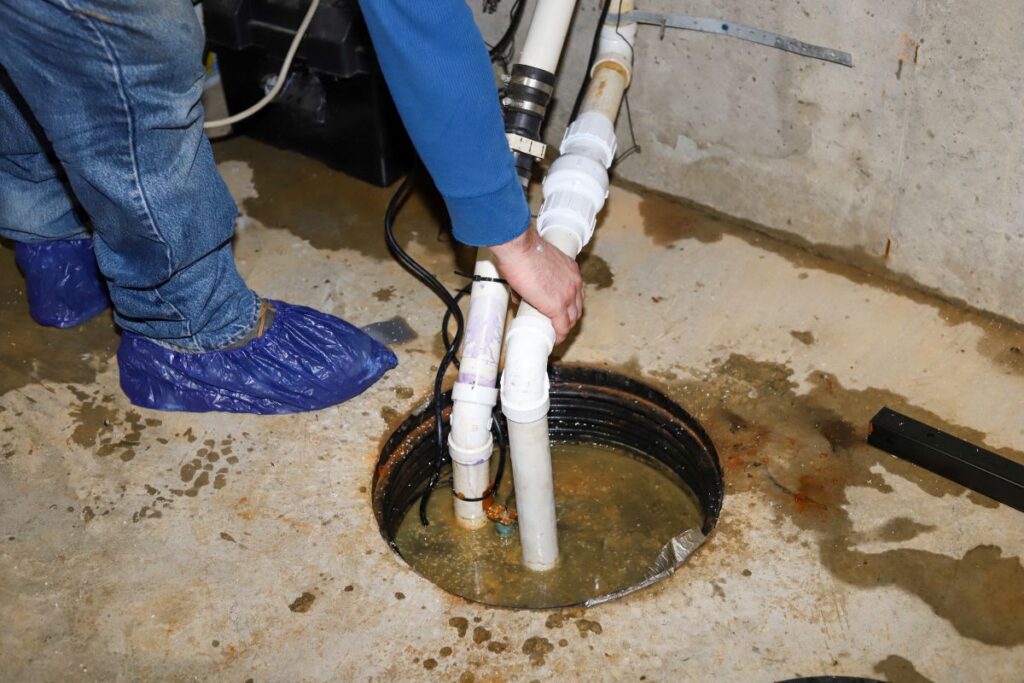 sump pump installation man holding pipe