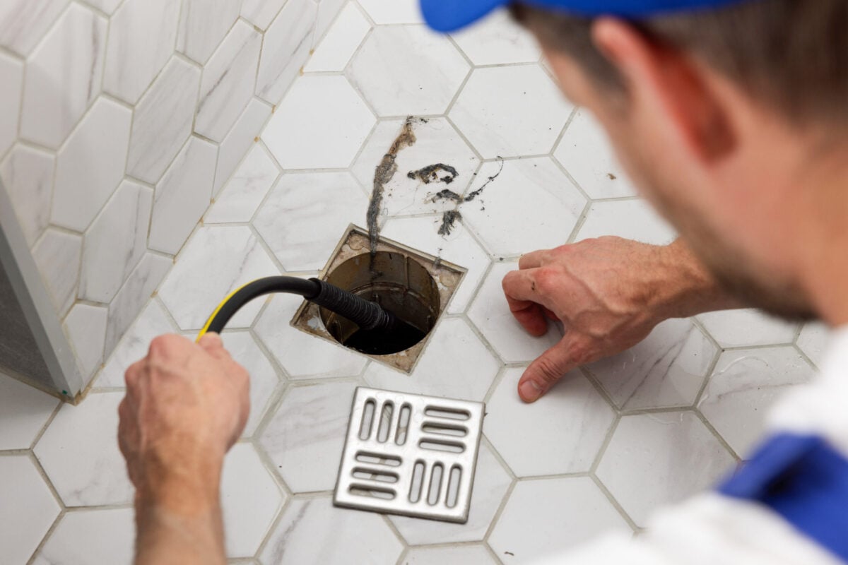 hydro jet drain cleaning plumber unclogging blocked shower drain with hydro jetting at home bathroom. sewer cleaning service
