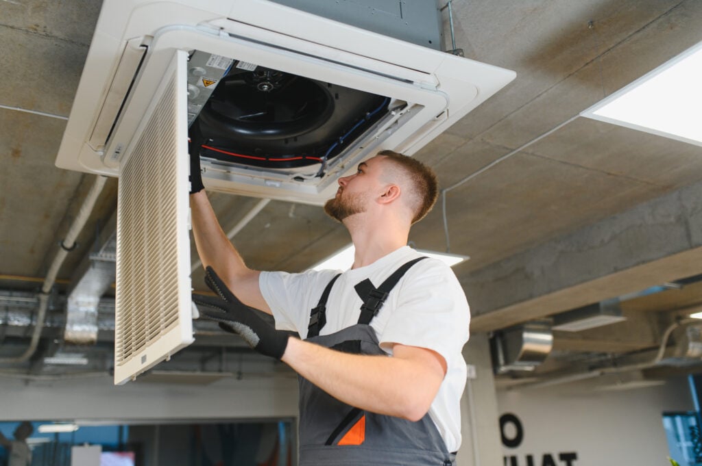 commercial ac unit Professional worker installing air conditioner filter, providing heating, ventilation, and air conditioning maintenance in office building