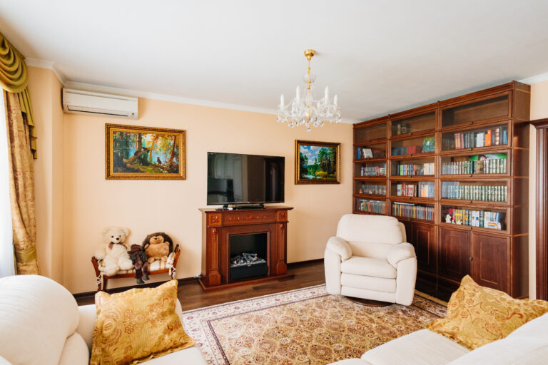 fireplace repair okemos Russia, Rostov-on-Don, 13.05.2022. The interior of the living room with a bookcase, fireplace, TV and paintings. Classic interior of the house for sale or rent.
