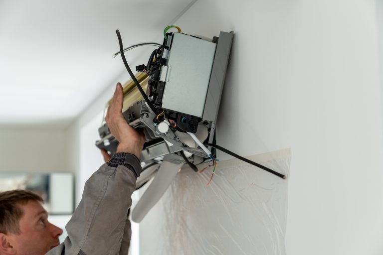 Man technician worker in uniform fixing repairing apartment air conditioner, installing wall-mounted mini split. AC unit maintenance concept