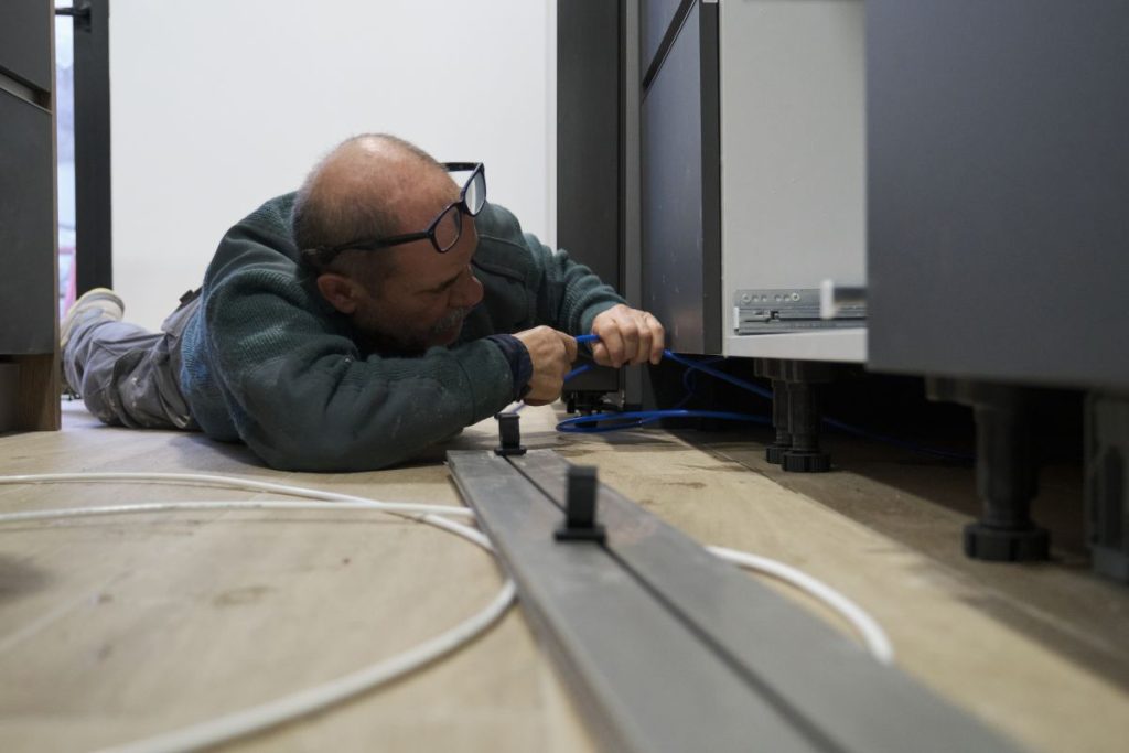 commercial refrigeration installation guy on the floor fixing unit